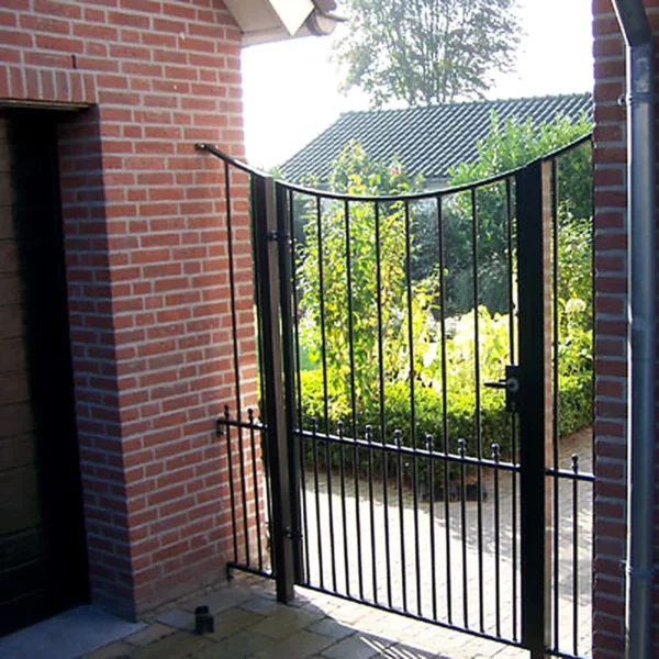 Sierlijk zwart stalen tuinpoortje met krulornament in gemetselde doorgang in Den Dungen.
