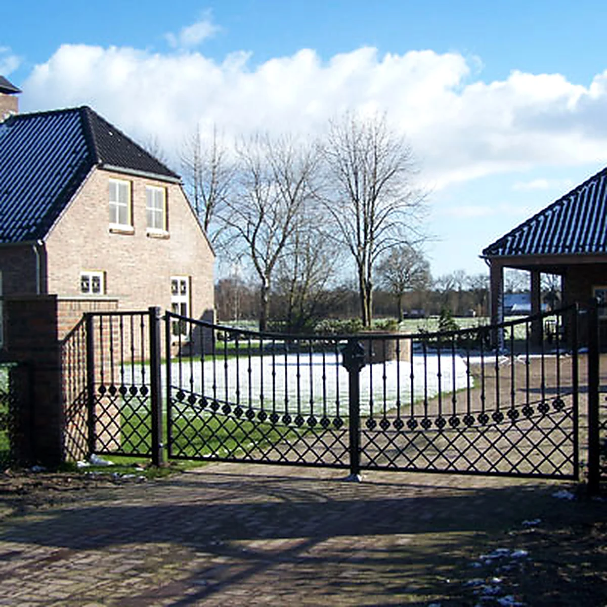 Dubbele zwarte sierpoort met ruitvormig spijlenpatroon voor een oprit in Heeswijk.