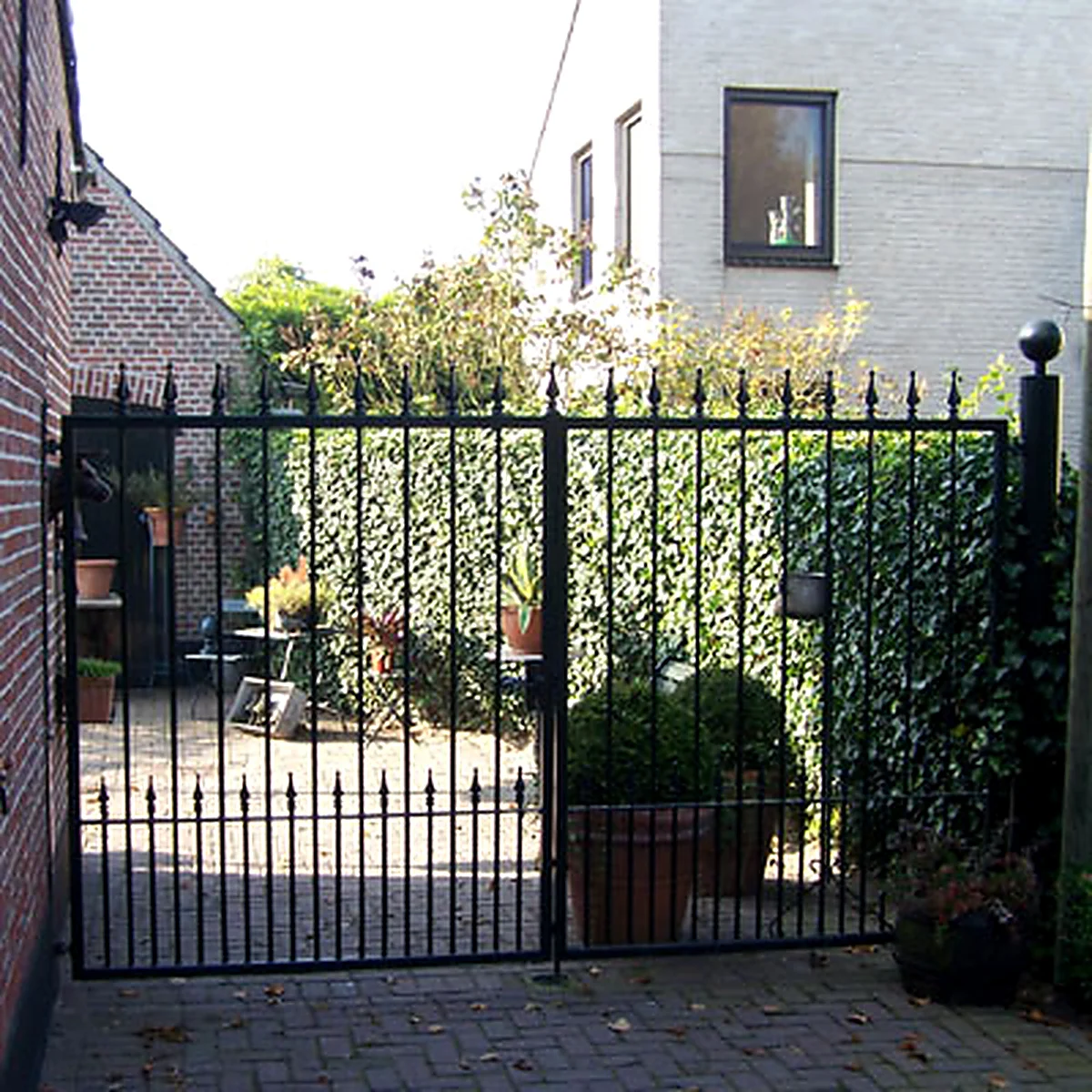 Dubbele zwarte stalen tuinpoort met rechte spijlen en sierpunten in Liempde.