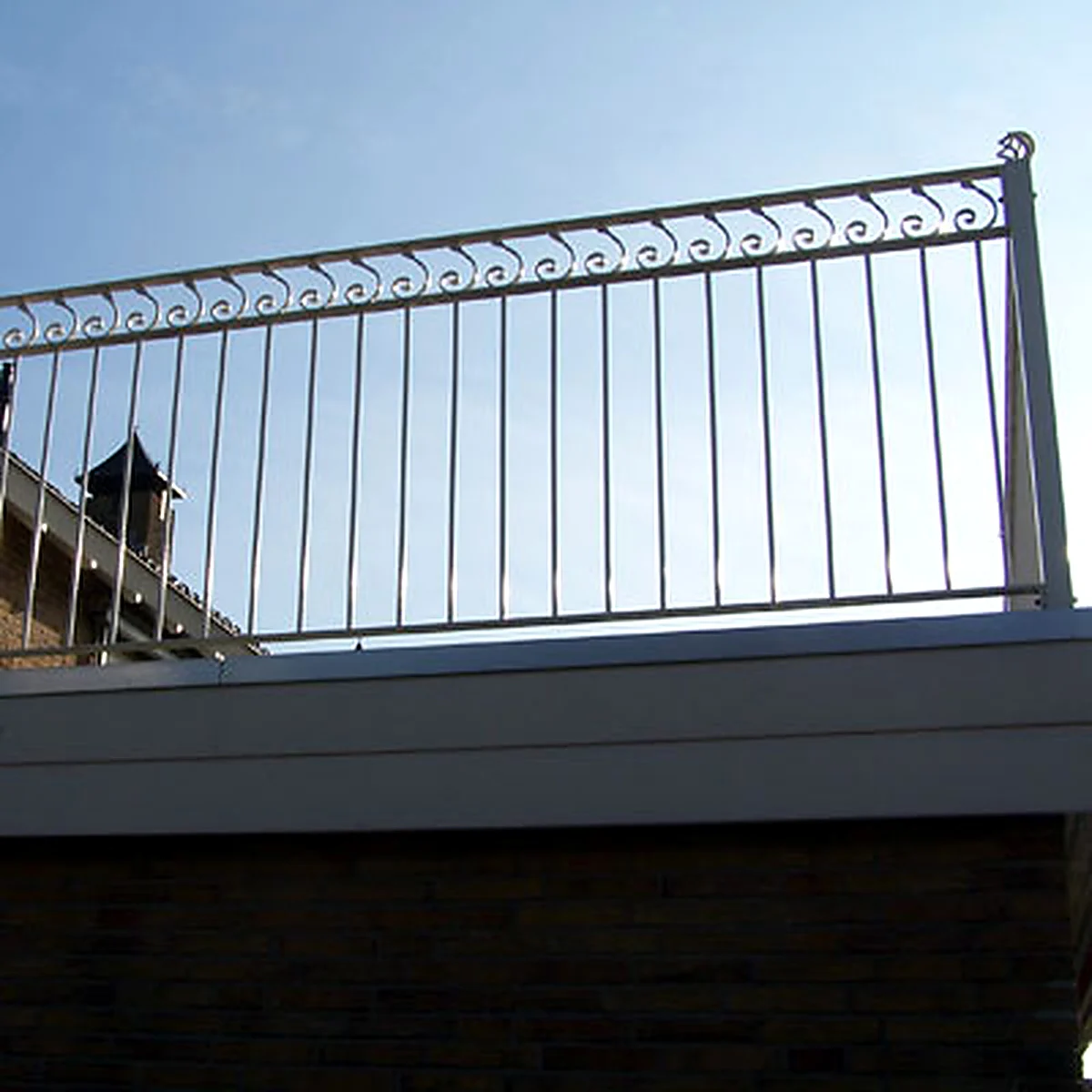 Stalen balkonhek met verticale spijlen en sierkrullen aan de bovenzijde in Oss.
