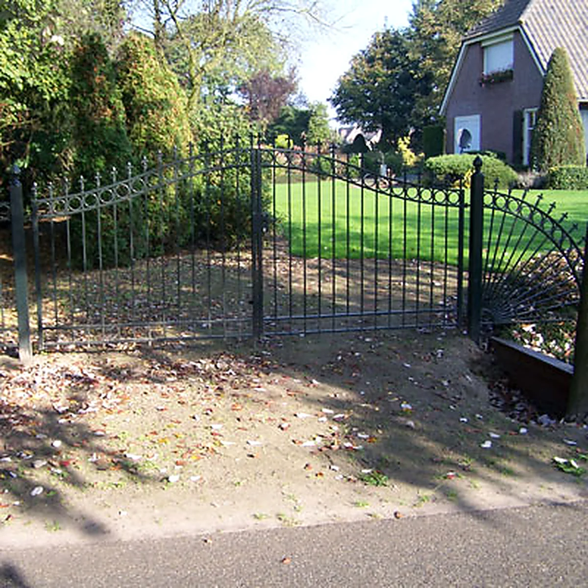 Dubbele zwarte stalen sierpoort met gebogen bovenrand en sierkrullen in Vinkel.