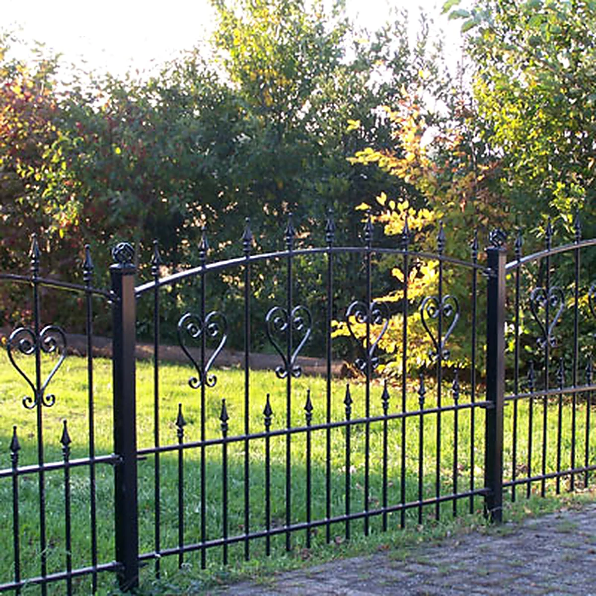 Zwart stalen sierhekwerk met spijlen, sierpunten en krulmotieven langs een tuin in Vinkel.